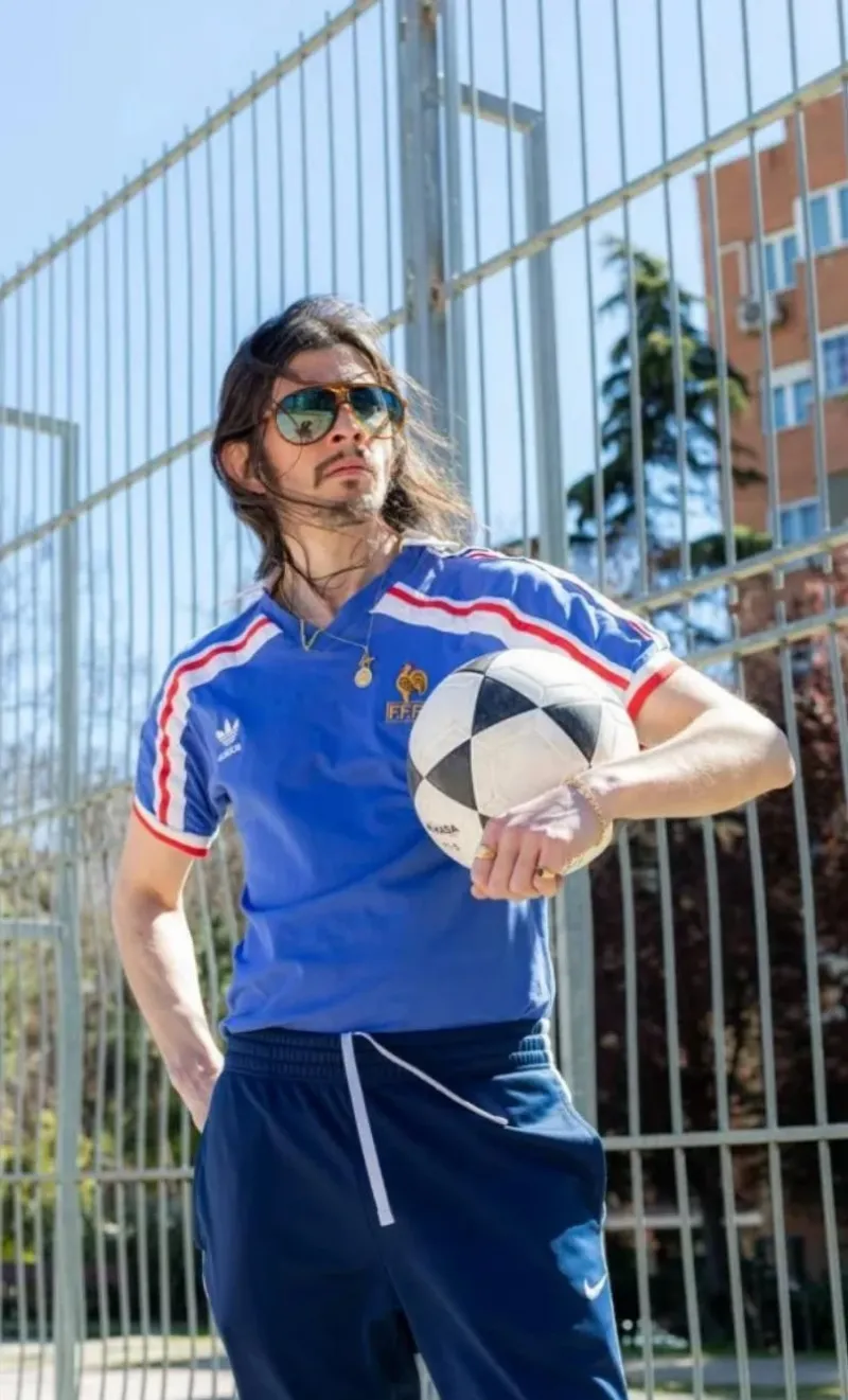 Hombre con camiseta azul retro de Francia, sujetando un balón